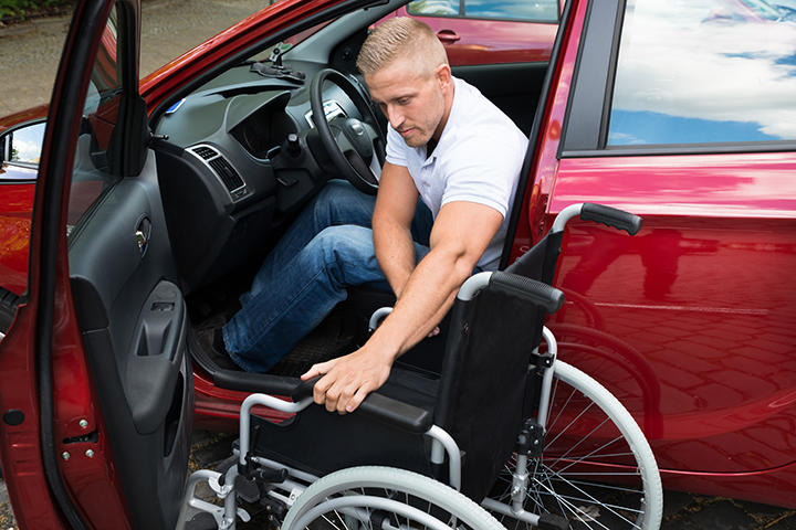 車いすを車に乗せる男性 車いすを車に乗せる男性