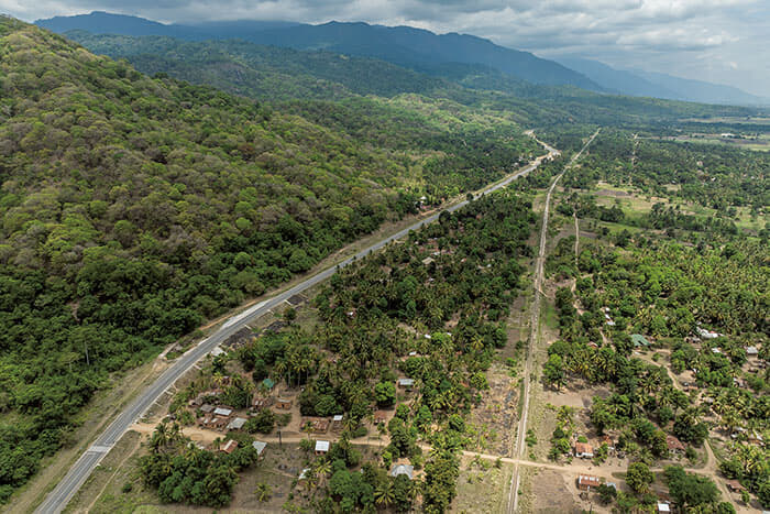 キベレッジ村近くのアスファルト道路によって、ウズングワ山脈と、耕作地や居住地とが隔てられている。道路に沿って走るのは、中国の出資などで1970年代に完成したタンザン鉄道<br />
