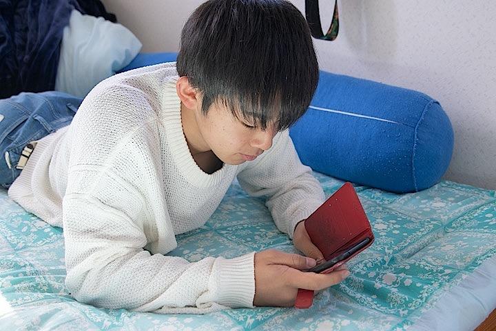 スマートフォンで動画を見る高校生 スマートフォンで動画を見る高校生